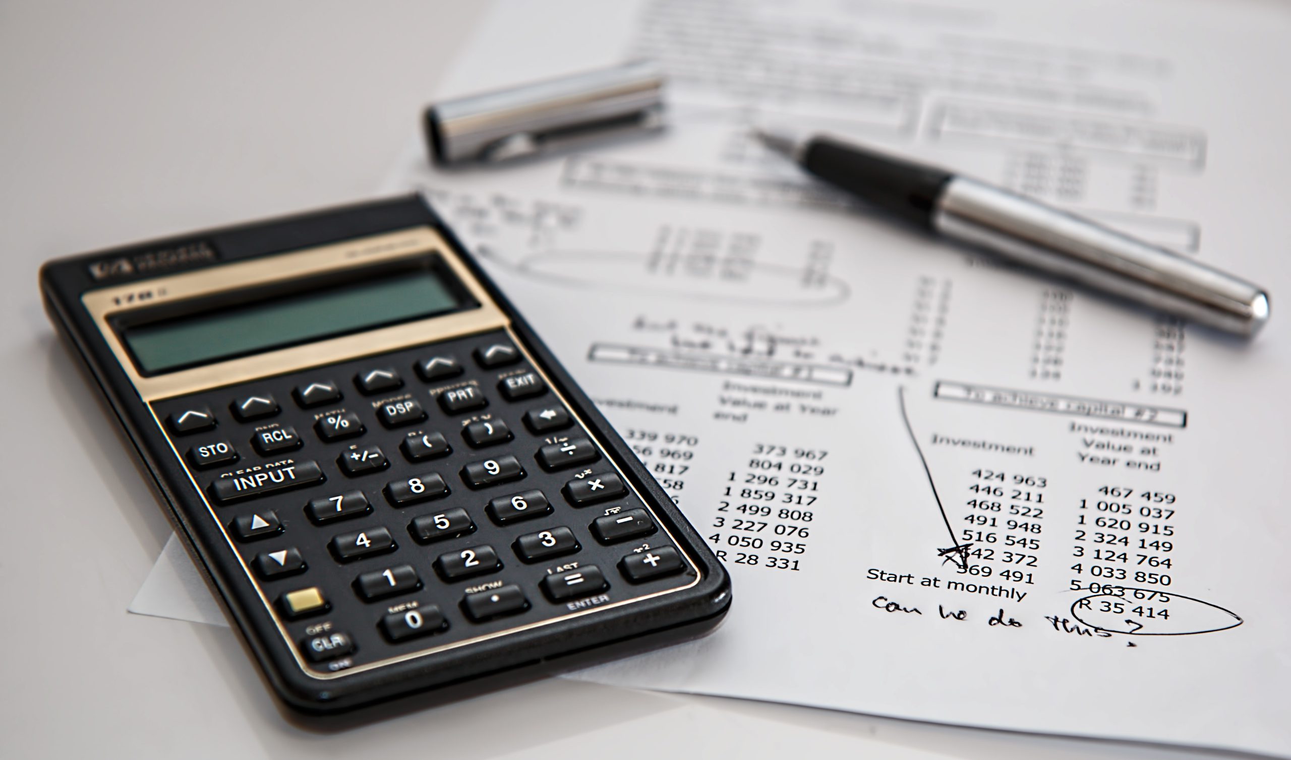 Calculator, pen, and financial worksheets on a desk