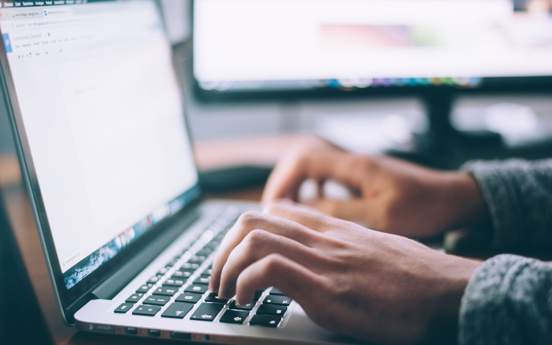 Hands typing on a laptop keyboard